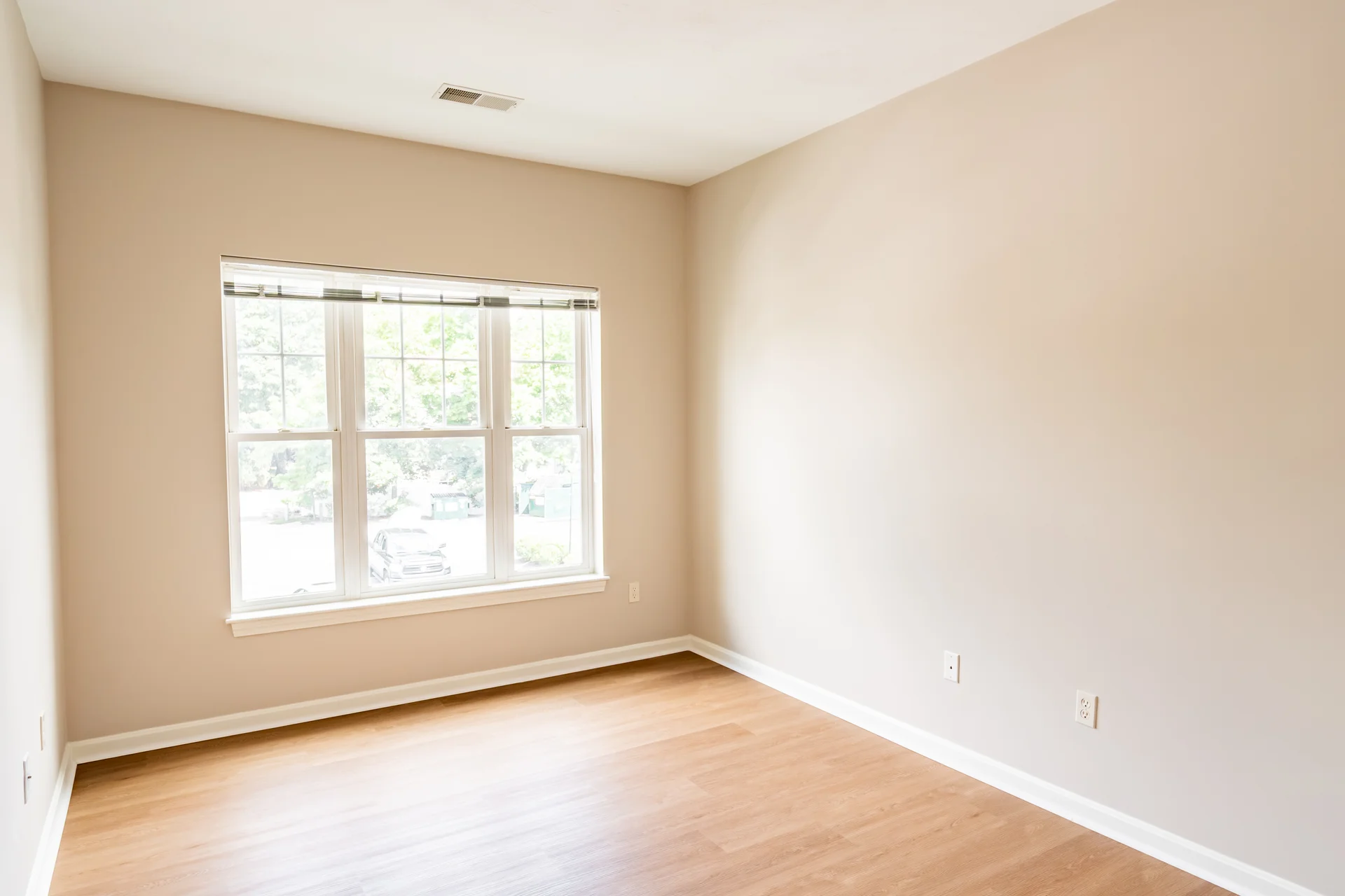 Bedroom with a wide triple window and new plank flooring.